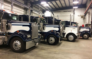 Four white and blue Liquids in Motion water hauling trucks parked in shop 
