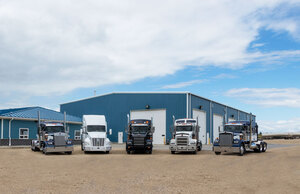 Liquids in Motion blue office and shop with five different colored bulk liquid transport trucks parked in a line.