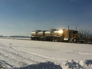 A large Liquids in Motion Ltd. water hauling truck driving in the winter.