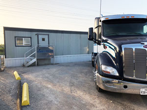 Liquids in Motion Ltd. transporting parked truck in front of an office.