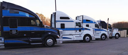 Black, white, and blue Liquids in Motion Ltd. trucks posed in a line. 